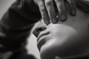 Close-up of a person's face with hand covering eye