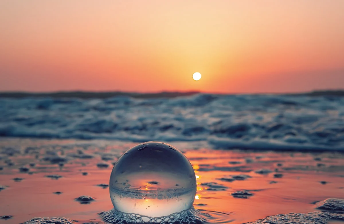 Relaxing Scene With Glass Ball On Calm Ocean Beach At Sunrise