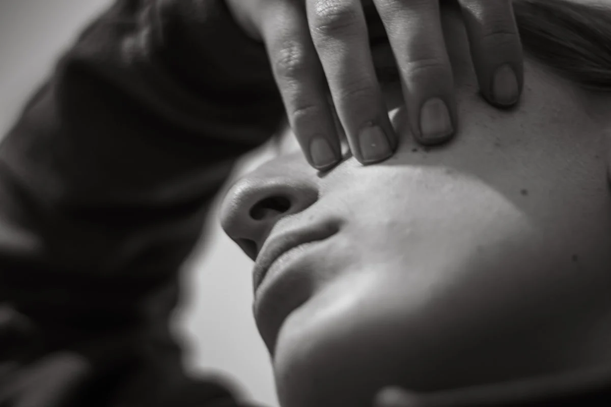 Close-up of a person's face with hand covering eye